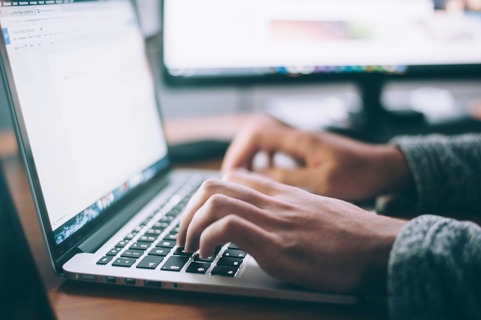 Persons hands typing on a laptop keyboard