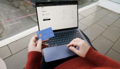Person paying for something on a laptop with their credit card out